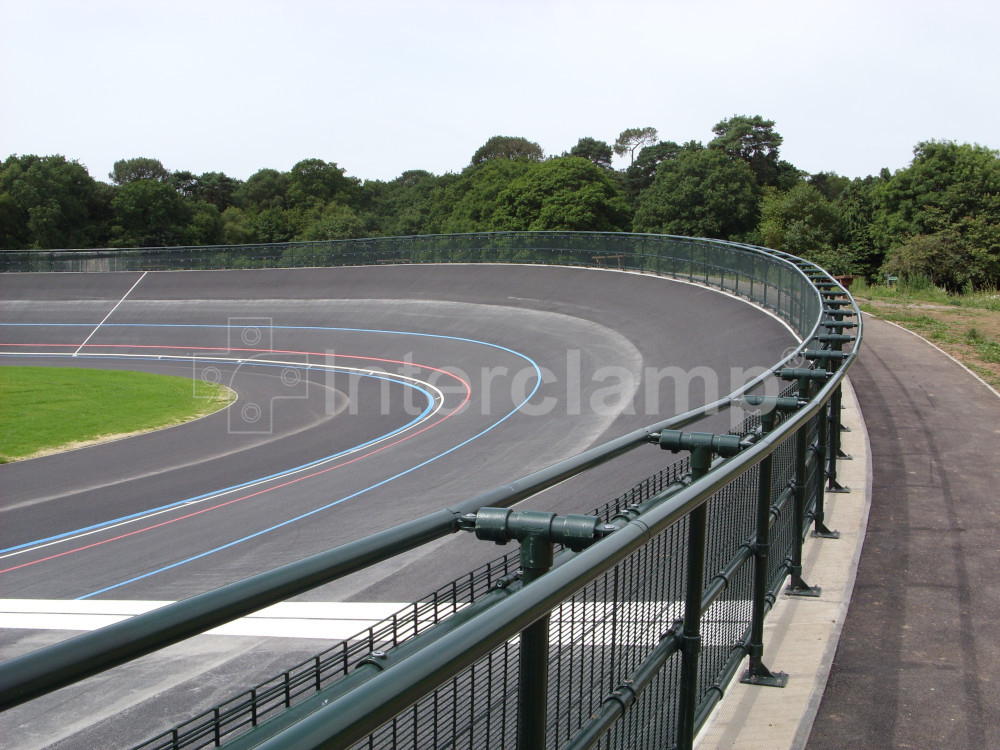 Dark green powder-coated Interclamp tube clamp DDA fittings used to construct a robust safety barrier around a velodrome, providing secure boundaries for cyclists